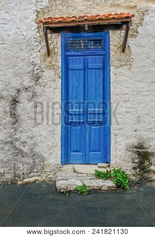 Old Building With Interesting Blue Wooden Doors That Are Closed.  Vibrant Blue In Colour And A Grill
