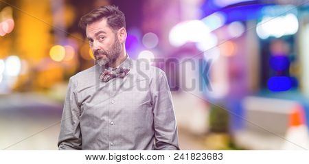 Middle age man, with beard and bow tie having skeptical and dissatisfied look expressing Distrust, skepticism and doubt at night club