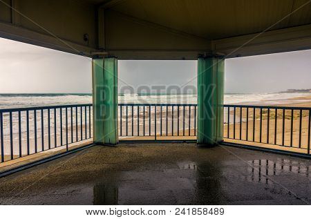 View through open windows of an empty beach in a overcast day