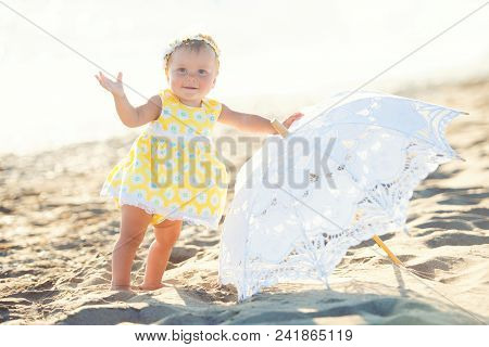 Lovely Little Girl On The Beach With An Umbrella.