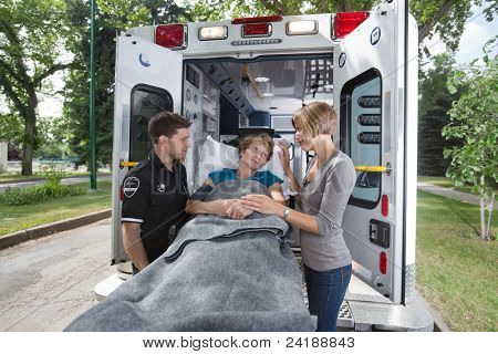Senior kvinde ser på datter / omsorgsperson mens ind i ambulance