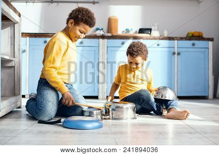 Funny Cacophony. Upbeat Little Kids Sitting On The Kitchen Floor And Drumming On Saucepans, Pretendi
