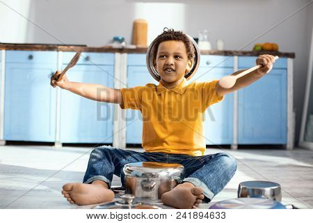 Little Drummer. Upbeat Little Drummer Sitting On The Kitchen Floor And Pretending To Be A Drummer Wh