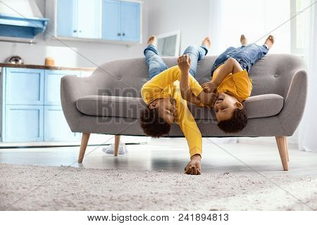 Playing Around. Cheerful Little Brothers Lying On The Sofa Upside Down And Tickling Each Other While