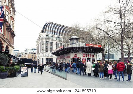 London, UK - April 2018: People queue for buying tickets from TKTS, the official London theatre ticket booth located at Leicester Square offering last minute and discount tickets for West End shows