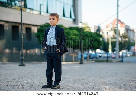 Concept Future Businessman. Concentrated Boy In Classic Modern Dark Blue Business Costume And Baby B