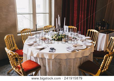 Round Table With Many Chairs Around Served For Many People In Retro Style With White Tablecloth, Lux