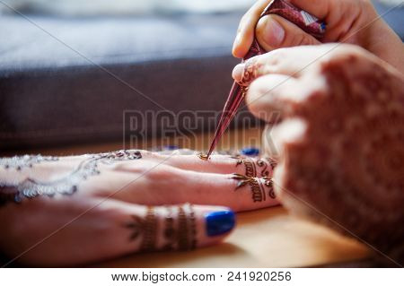 Drawing Mehndi On The Hand Of A Girl