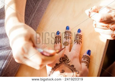 Drawing Mehndi On The Hand Of A Girl