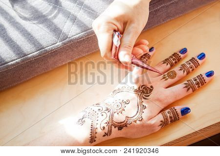 Drawing Mehndi On The Hand Of A Girl