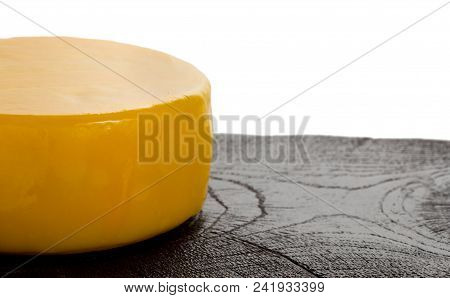 Round Head Of Delicious Cheese On Textured Black Wooden Oak Cutting Board, Close Up.