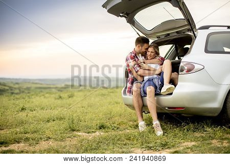 Loving Couple Sitting In The Car Trank