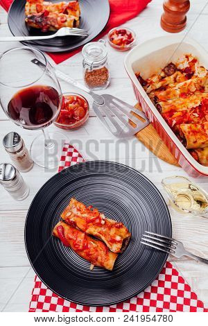 Italian Cannelloni Stuffed With Minced Meat And Served With Tomato Sauce On Black Plates. Dinner For