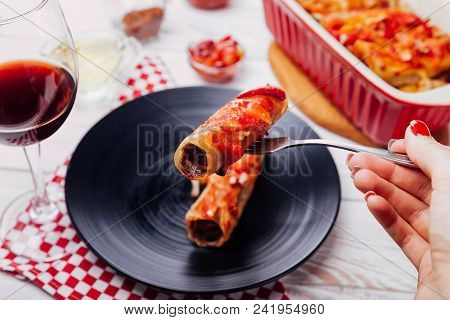 Italian Cannelloni Stuffed With Minced Meat And Served With Tomato Sauce And Red Wine On Black Plate
