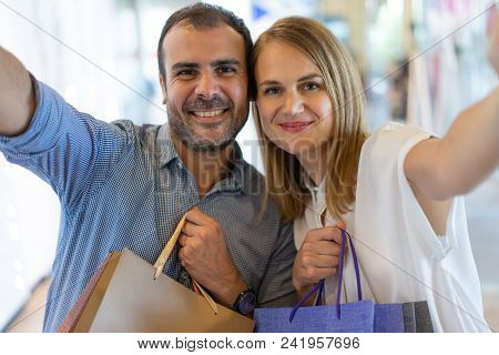 Happy Family Couple Enjoying Weekend In City Mall. Selfie Portrait Of Smiling Man And Woman With Pap
