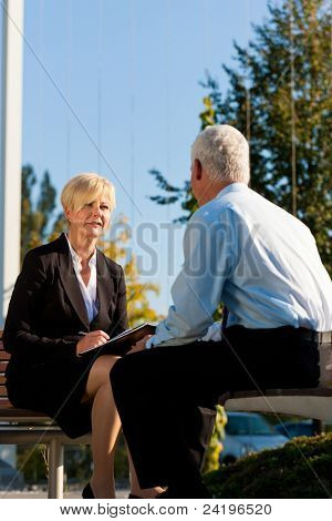 Business coaching udendørs - en mand og en kvinde har en coaching diskussion