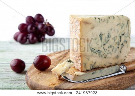 Stilton On A Cheese Board With Red Grapes And Cheese Knife