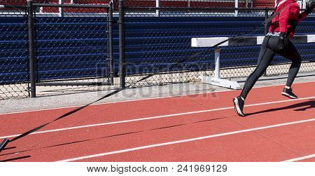 A Runner Is Running With Resistance On A Cold Day At Winter Track And Field Practice On A Red Track 