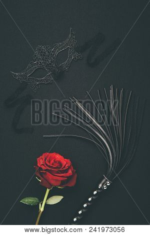 Lacy Mask And Black Whip With Rose Flower Isolated On Black