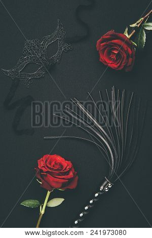 Black Whip And Lacy Mask With Rose Flowers Isolated On Black