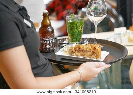 Waitress Carries On A Tray Beer, Tea, And Cake To The Client Of The Hotel Bar. Waitress Serving A Cl