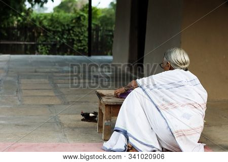 November 30, Maharashtra India, - An Elderly Lady In White Dress Reading Books In The Evening At Gan