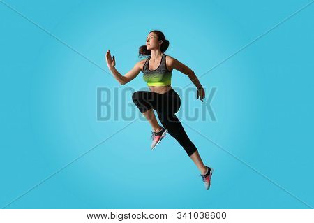 Athletic Young Woman Running On Light Blue Background, Side View