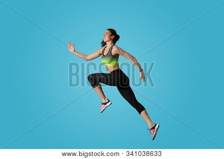 Athletic Young Woman Running On Light Blue Background, Side View