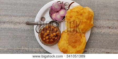 Chole Bhature: Indian dish spicy Chick Peas curry also known as Chole or Chana Masala is traditional North Indian main course recipe & usually served with fried puri / Bhature with Onion Salad .