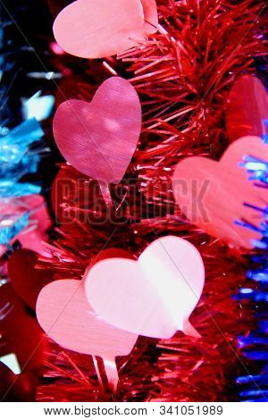 Red Tinsel With Bright Hearts On A Blue Background, Selective Focus. Love Concept Valentine Day, Ver