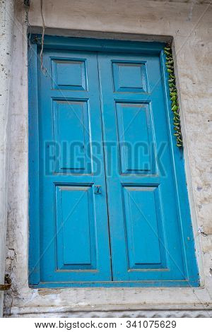 Bright Blue Door In An Alley In Old Delhi India. Green Chillies Tied On A Thread Hanging To Keep Awa