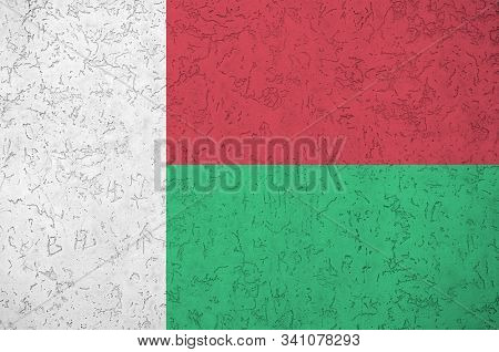 Madagascar Flag Depicted In Bright Paint Colors On Old Relief Plastering Wall. Textured Banner On Ro