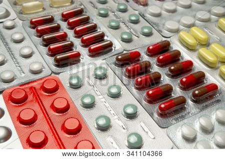 Multi-colored Tablets, Capsules And Vitamins In Blister Packs Arranged In A Background