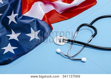 Doctors Stethoscope And Us Flag On A Blue Background. Usa Medicine Concept, High Level, Medical Insu