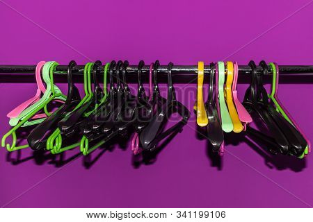 Many Empty Multi-colored Plastic Hangers Hanging On A Metal Rack With A Reassigned One. Group Of Dif