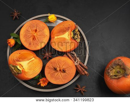 Delicious Fresh Persimmon Fruit On A Black Background. Persimmon Slices On A Black Plate. Top View. 