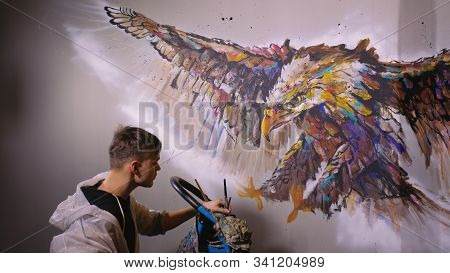 Artist Designer Draws An Eagle On The Wall. Craftsman Decorator Paints Picture With Acrylic Oil Colo