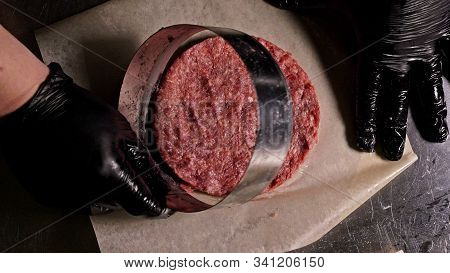 Cook Makes Meat Medallions For Burgers. Chef In Black Food Gloves Makes Cutlet. Cutlets Are Leveled 