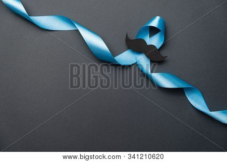 Light Blue Ribbon With Mustache On Black Background. Prostate Cancer Awareness, Movember Men's Healt
