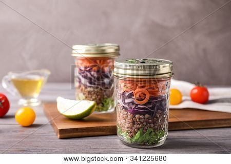 Glass Jars With Healthy Meal On Light Grey Wooden Table