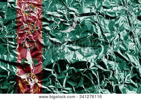 Turkmenistan Flag Depicted In Paint Colors On Shiny Crumpled Aluminium Foil Closeup. Textured Banner