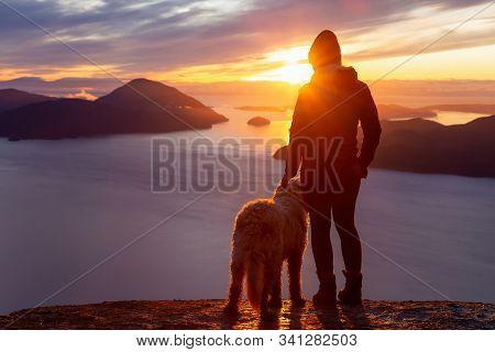 Adventurous Girl Hiking On Top Of A Mountain With A Dog During A Colorful Sunset. Taken On Tunnel Bl
