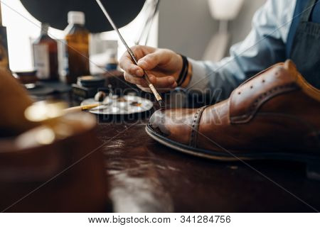 Bootmaker with brush tints shoes, footwear repair