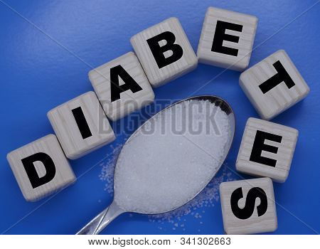 Word Diabetes On Cubes With A Spoonful Of Sugar On A Blue Background