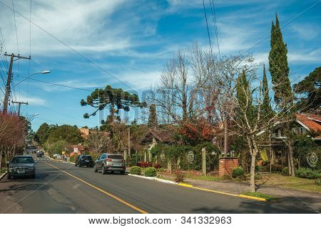 Gramado, Brazil - July 21, 2019. Gardened Houses And Trees On Empty Paved Street With Parked Cars, I