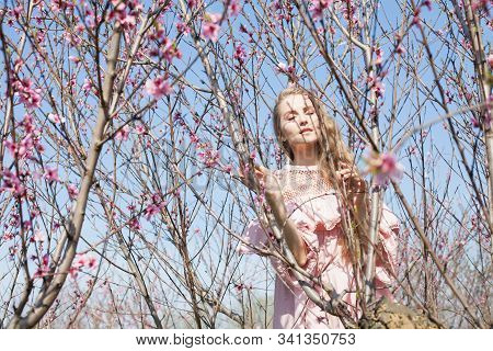 Beautiful Blonde Woman In Pink Dress Walks Through The Flowering Garden Spring