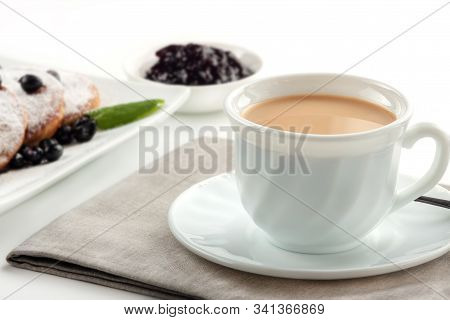 A Cup Of Coffee With Milk And A Plate With A Pancakes Is On The Table.