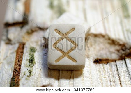 Wooden Rune Inguz Close-up On A Wooden Background. Soft Focus