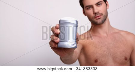 Bare Sexy Beauty Strong Man Holds In His Right Hand Gray Deodorant And Looks At Frame. Hygiene, Armp