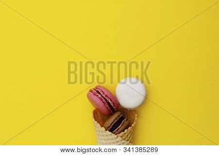 Macarons Cakes. Stil Life Photo Of Waffle Cone With Macaroons On Yellow Background. Flat Lay, Desser